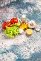 Free photo top view fresh green salad with oil and tomatoes on light-blue background