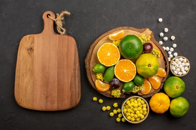 Top view of fresh green tangerines with feijoas and candies on dark