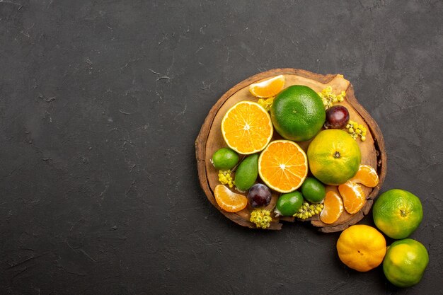 Top view of fresh green tangerines with feijoas on dark