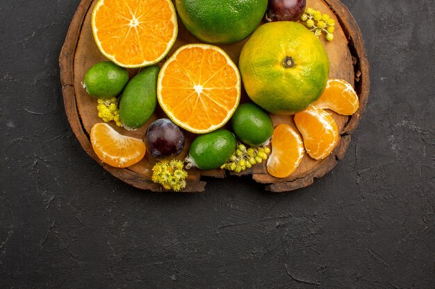 Top view of fresh green tangerines with feijoas on dark