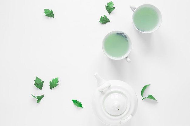 Вид сверху свежего зеленого чая с чайными листьями и чайником