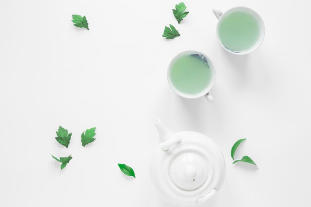 Top view of fresh green tea with tea leaves and teapot