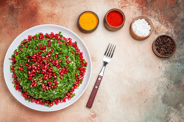 Top view fresh greens with peeled pomegranates on light desk greens fruit meal