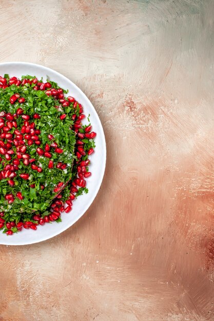 Top view fresh greens with peeled pomegranates on light floor fruit green color