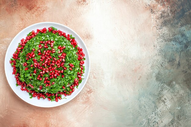 Top view fresh greens with peeled pomegranates on a light table fruit green color