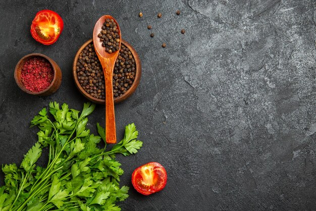 Top view of fresh greens with pepper and tomatoes on a grey surface