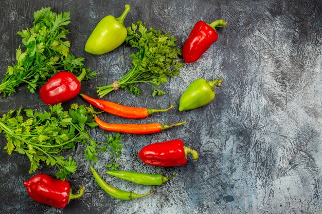 Top view fresh greens with peppers on light-grey table