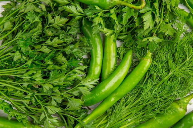 Free photo top view fresh greens with peppers on a white background