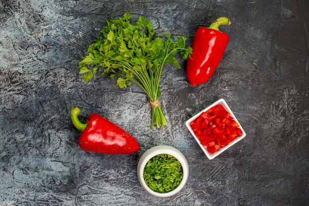 Top view fresh greens with red bell-peppers on a light-grey table