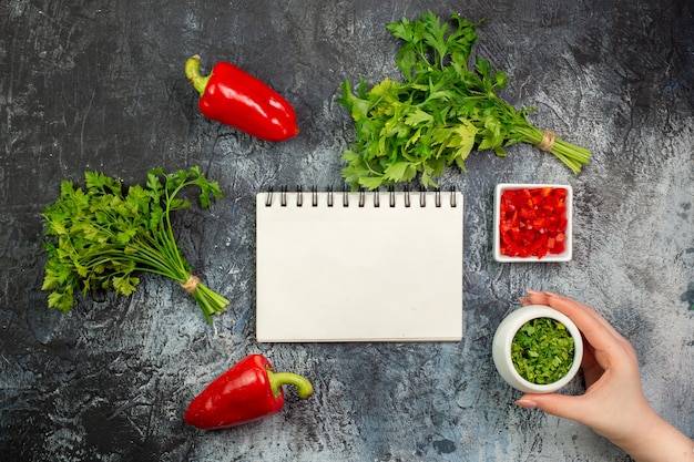 Top view fresh greens with red bell-peppers on light-grey table