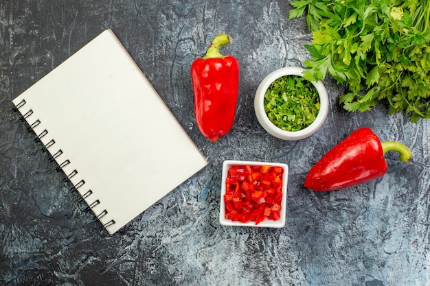 Top view fresh greens with red bell-peppers on light-grey table