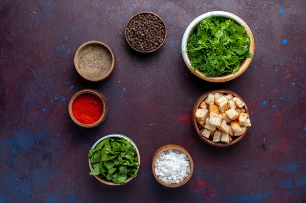 Top view fresh greens with rusks and seasonings on dark table, meal soup green food