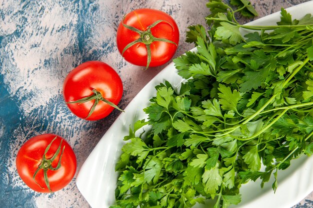 Top view fresh greens with tomatoes on a light-blue background