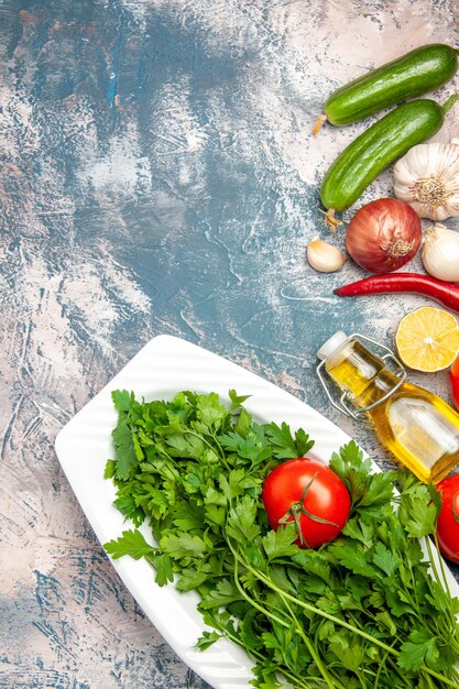 Top view fresh greens with tomatoes on light-blue background