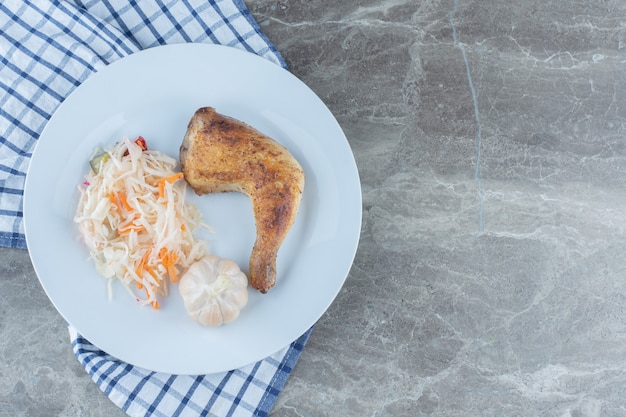 白いプレートに焼きたてのチキンレッグとザワークラウトの上面図。