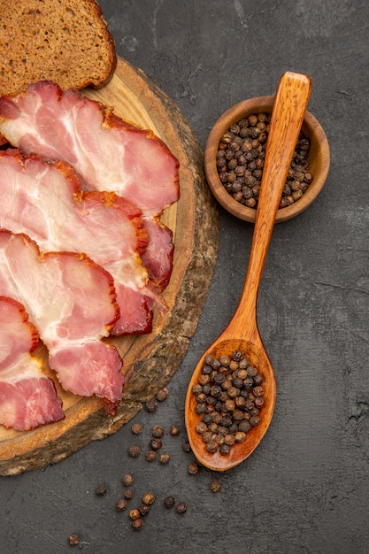 Foto gratuita fette di prosciutto fresco vista dall'alto con panini e fette di pane su sfondo scuro