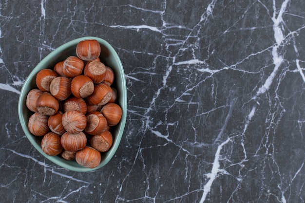 Top view of fresh hazelnuts in blue bowl.