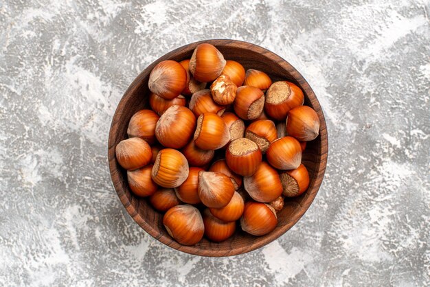 Top view of fresh hazelnuts inside plate on white surface