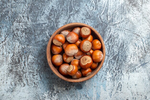 Top view fresh hazelnuts inside plate on white surface