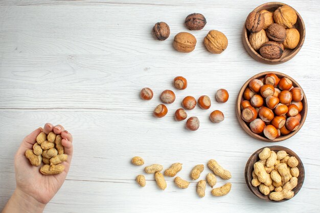 Top view fresh hazelnuts with peanuts and walnuts on white table