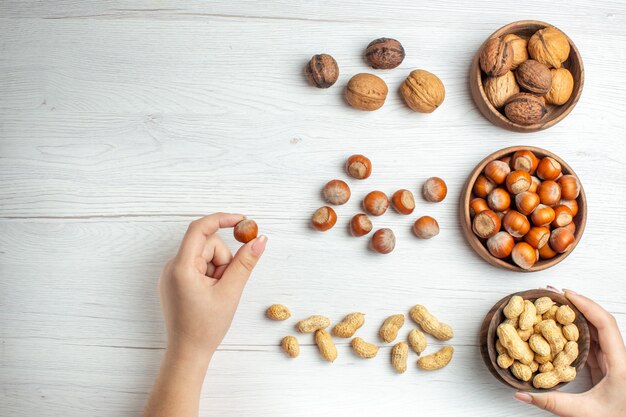 Top view fresh hazelnuts with peanuts and walnuts on white table