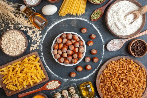 Top view fresh hazelnuts with raw pasta oil eggs and flour on dark background bake dough photo meal kitchen color