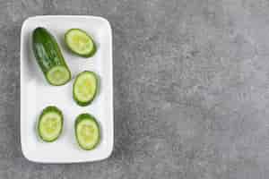 Free photo top view of fresh healthy cucumbers n white plate over grey table.