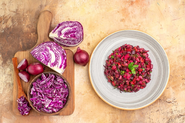 Top view fresh ingredients on a wooden cutting board togehter with delicious salad on a ceramic plate together on a wooden background with space for text