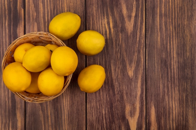 Vista dall'alto di limoni freschi e succosi su un secchio con limoni isolato su una superficie in legno con spazio di copia