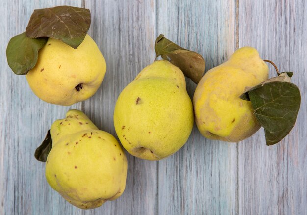 Top view of fresh and juicy quince fruits with leaves on a grey wooden background