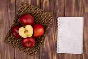 Foto gratuita vista dall'alto di mele fresche succose e rosse su un vassoio di vimini su una parete in legno con spazio di copia