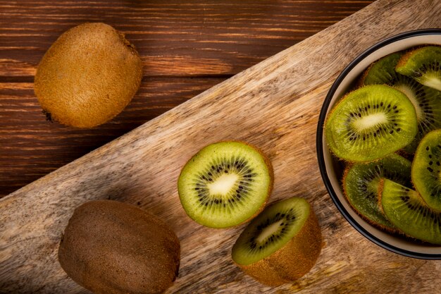 Top view of fresh kiwi fruit and slices of kiwi on a wooden cutting board on rustic