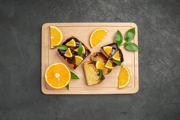 Top view of fresh lemon slices and chopped cake slices on dark background