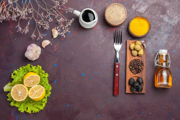 Top view of fresh lemon slices with green salad on dark