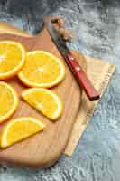 Foto gratuita vista dall'alto di fette di limone fresche con coltello su tagliere di legno su giornale sul lato destro dello sfondo grigio