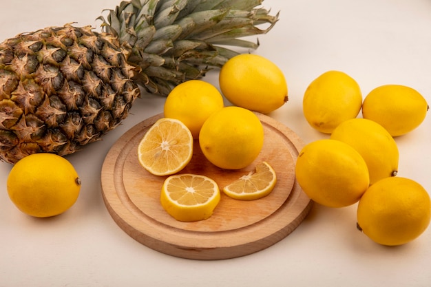 Top view of fresh lemon slices on a wooden kitchen board with pineapple and lemons isolated on a white wall