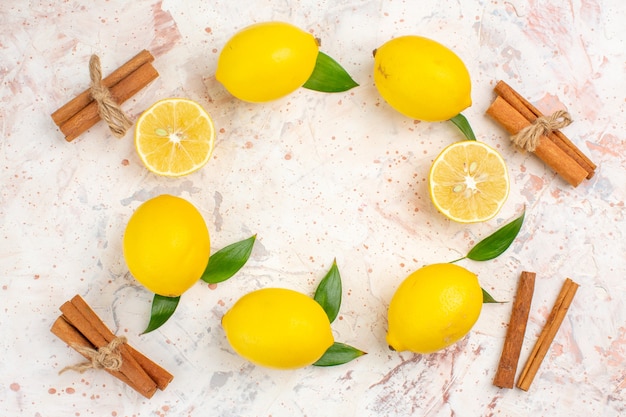 Vista dall'alto di limoni freschi a forma di cerchio, limoni tagliati a bastoncini di cannella sulla brillante superficie isolata