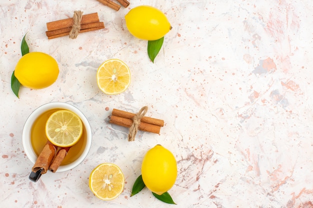 Top view fresh lemons cut lemon cinnamon sticks a cup of lemon tea on bright isolated surface free space