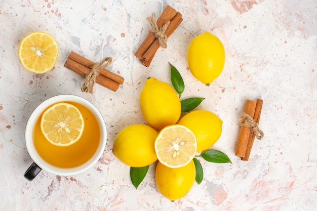 Top view fresh lemons cut lemon cinnamon sticks a cup of lemon tea on bright isolated surface