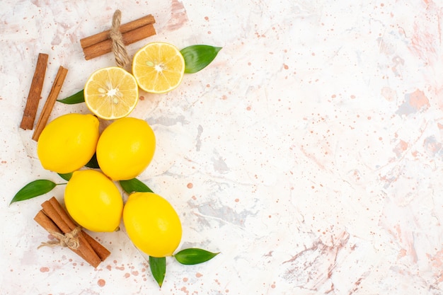 Top view fresh lemons cut lemons cinnamon sticks at the left of bright isolated surface free space