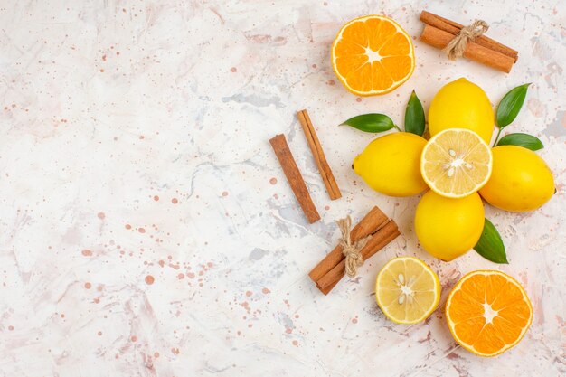 Top view fresh lemons cut orange cinnamon sticks on bright isolated surface free place