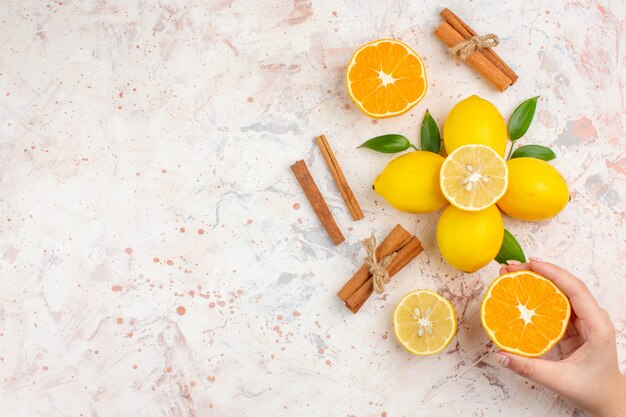Top view fresh lemons cut orange cinnamon sticks cut orange in female hand on bright isolated surface free space