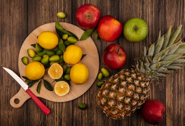 Top view of fresh lemons isolated on a wooden kitchen board with apples and pineapples isolated on a wooden surface