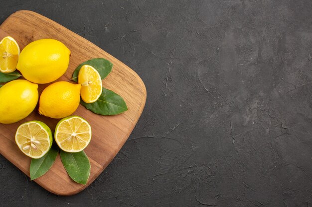 Top view fresh lemons sour fruits on the dark-grey table citrus lime fruit