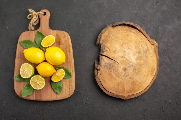 Top view fresh lemons sour fruits on dark-grey table citrus lime fruits