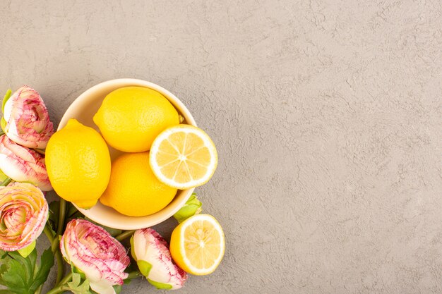 A top view fresh lemons sour ripe whole mellow citrus tropical vitamine yellow along with dried flowers on the cream desk