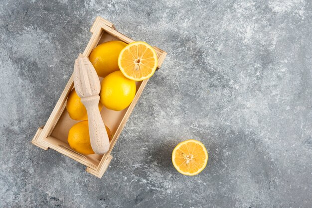 Top view of fresh lemons in wooden box over grey surface. 