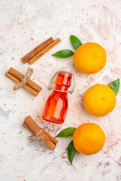 Top view fresh mandarines cinnamon sticks bottle on bright surface