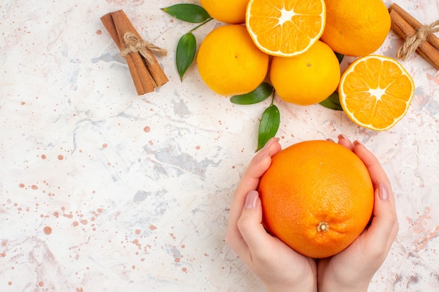 Top view fresh mandarines cinnamon sticks cut orange in woman hands on bright isolated surface free place