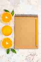 Free photo top view fresh mandarines cut mandarines cinnamon sticks pencil on notebook on bright isolated surface